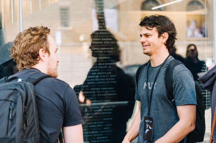 a man talking to another man in front of a building