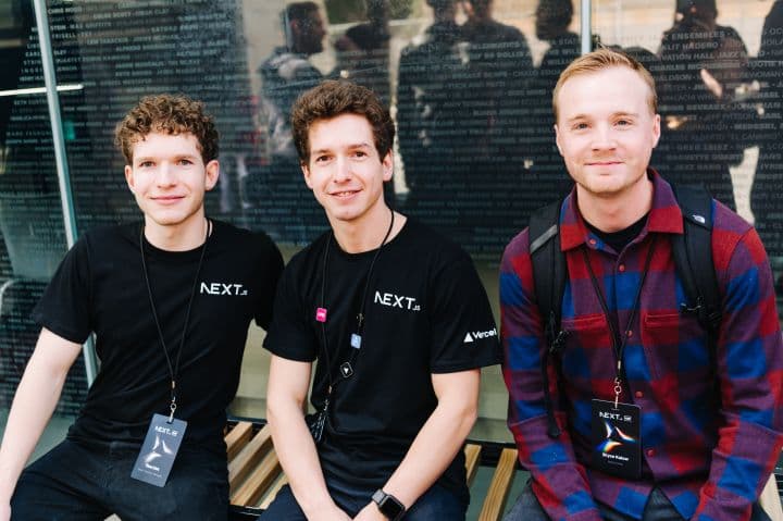 three young men sitting on a bench in front of a building