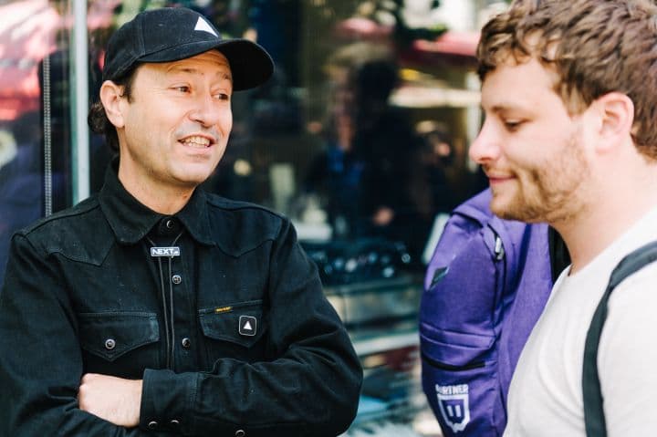 two men standing next to each other in front of a building