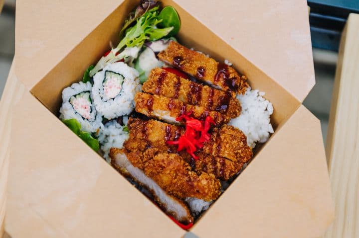 a box of sushi and rice on a table