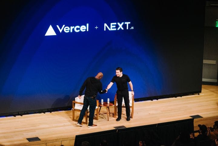 two men standing on a stage shaking hands