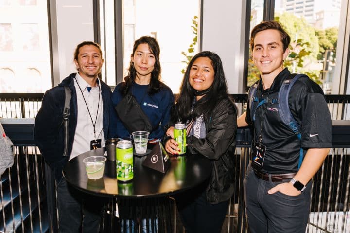 a group of people standing around a table with drinks