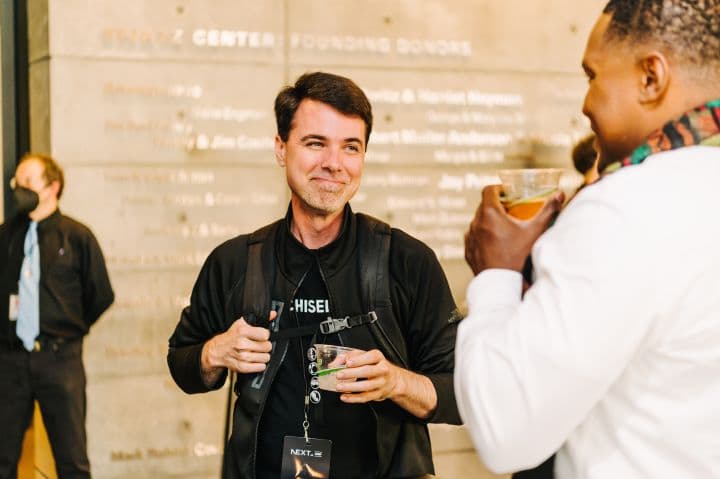 a man standing next to another man holding a drink