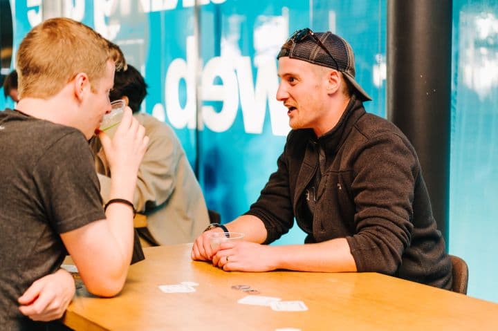 a man sitting at a table talking to another man