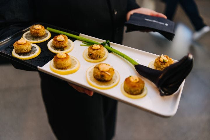 a person holding a tray of appetizers with asparagus