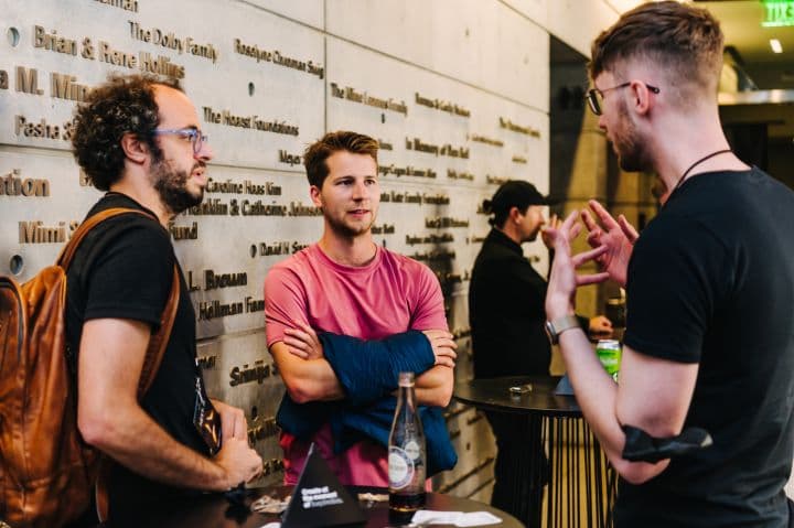 a group of men standing next to each other in front of a wall