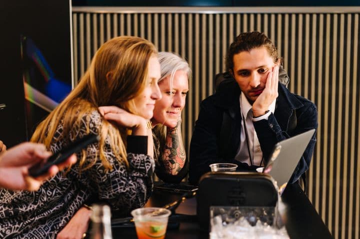 a group of people sitting around a laptop computer