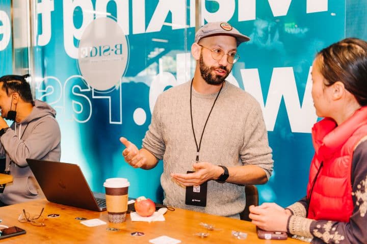 a man standing in front of a table with a laptop