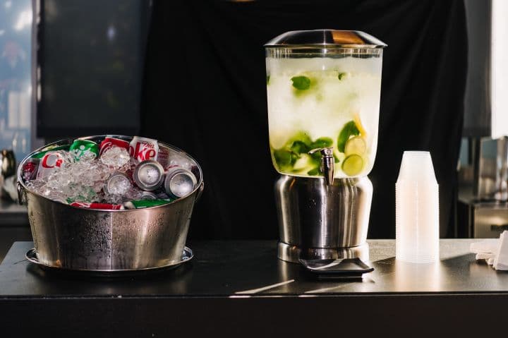 a pitcher of soda and a cup of soda on a table