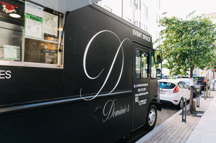 a black food truck parked on the side of a street