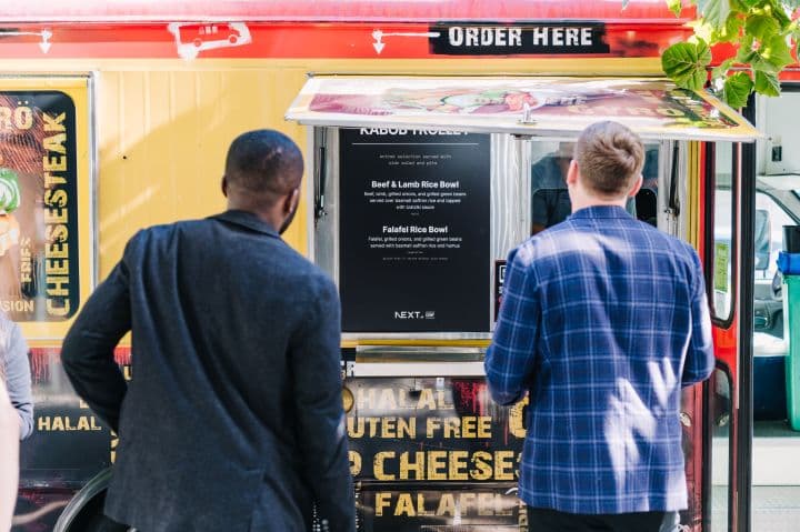 a group of people standing outside of a food truck