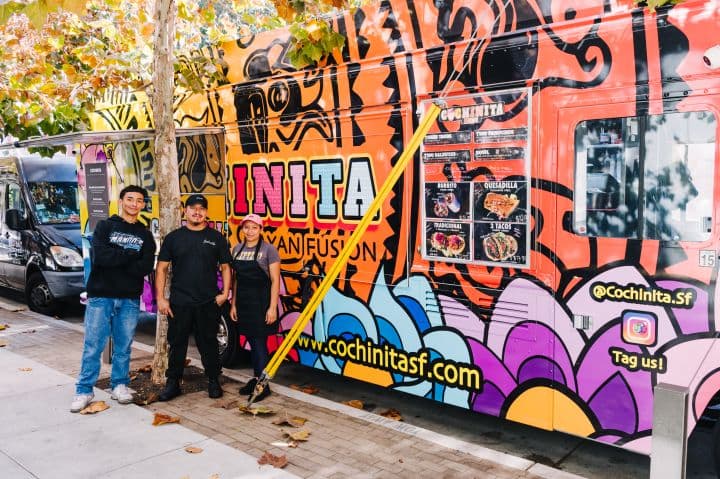 a group of people standing next to a colorful bus