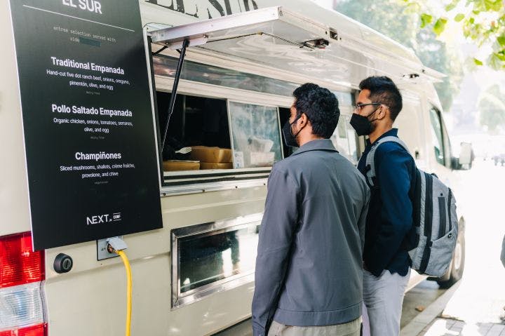 two men standing in front of a food truck