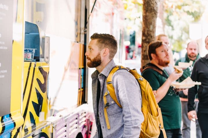 a group of men standing around a food truck