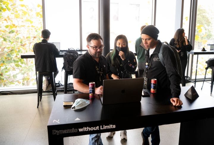 a group of people standing around a table with a laptop