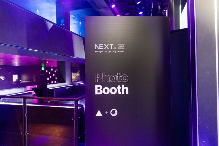 a photo booth with purple lighting and a sign