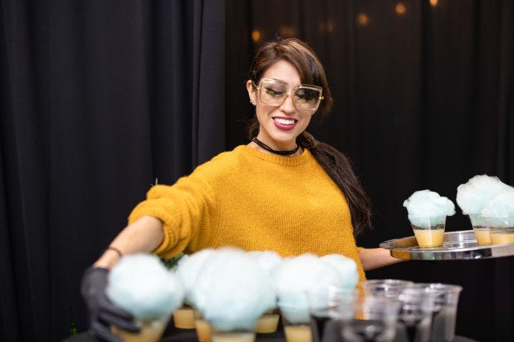 a woman holding a tray with cupcakes on it