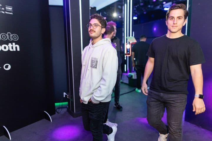 two men standing next to each other in front of a booth