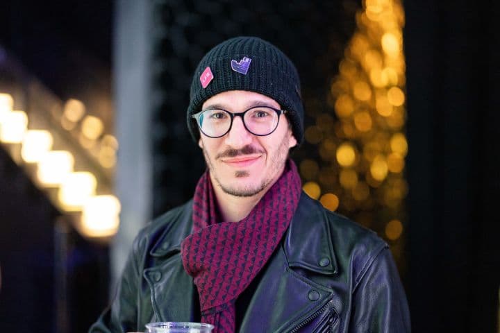 a man wearing a hat and scarf holding a drink