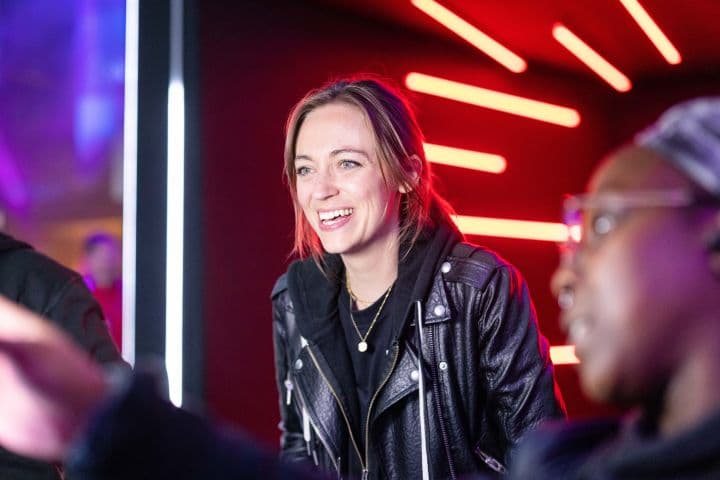 a woman in a leather jacket talking to a group of people