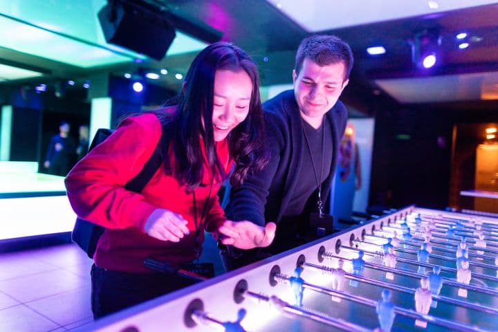 a man and a woman standing in front of a foo - ball table