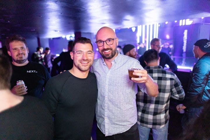 two men standing next to each other at a party