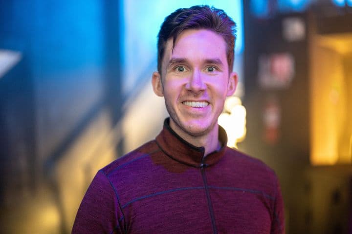 a man in a purple shirt smiling at the camera