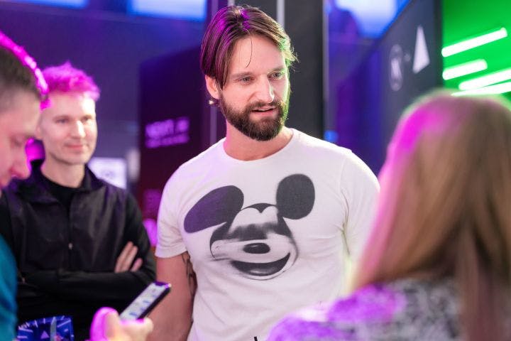 a man in a mickey mouse t - shirt talking to a group of people