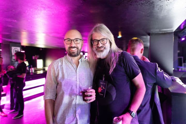 two men standing next to each other in a room