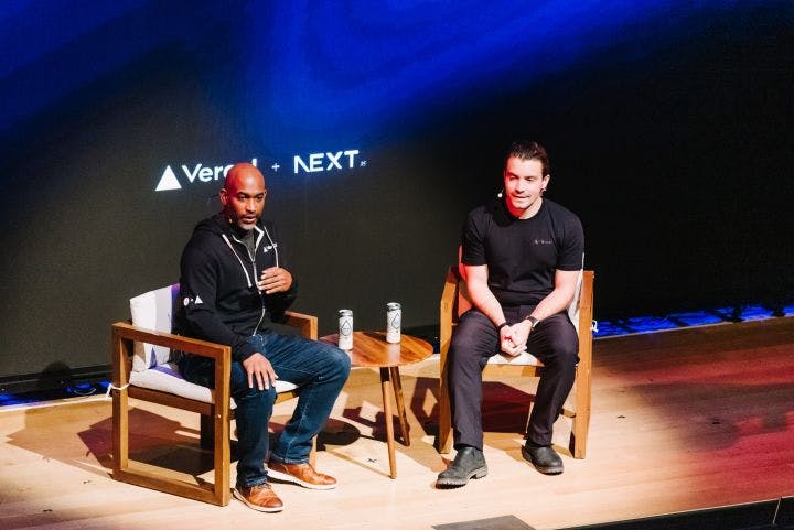 two men sitting in chairs on a stage